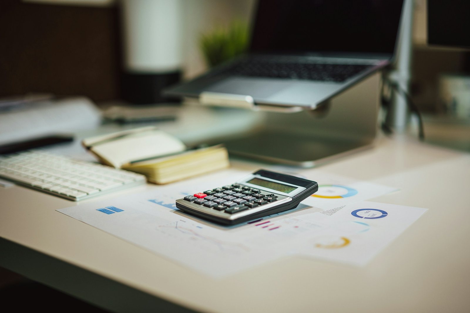 Calculator, cost charts and laptop on a desk
